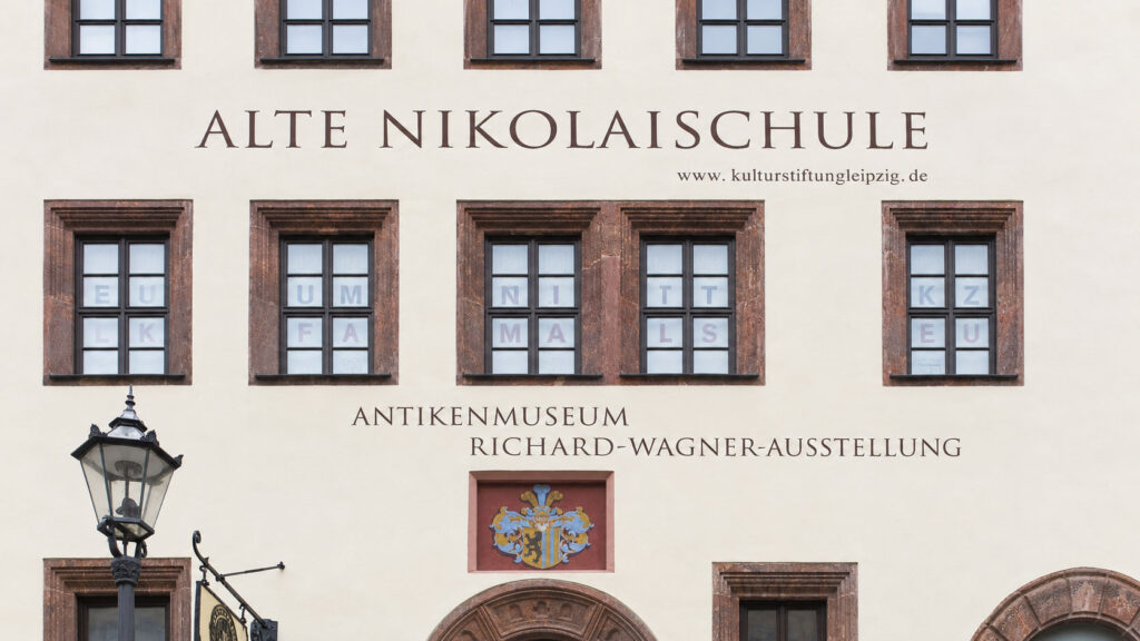 Außenansicht der Alten Nikolaischule in Leipzig mit den Schriftzügen „Alte Nikolaischule“, „Antikenmuseum“ und „Richard-Wagner-Ausstellung“.
